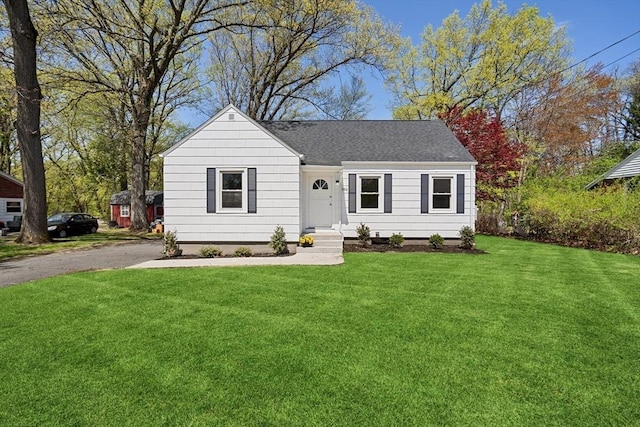 ranch-style home with a shingled roof and a front lawn