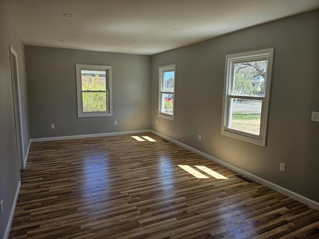 spare room with baseboards, dark wood-style floors, and plenty of natural light