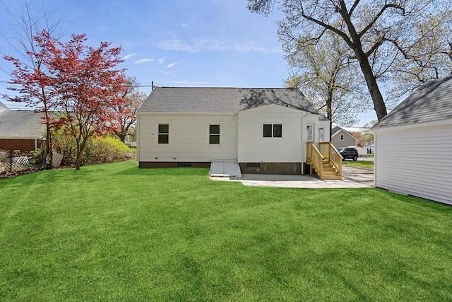back of house featuring roof with shingles, a yard, and a patio area