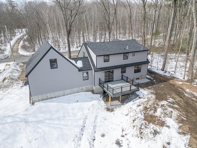 snow covered house with a wooden deck