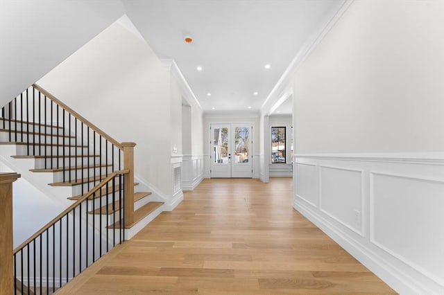 entryway featuring french doors, crown molding, and light hardwood / wood-style floors