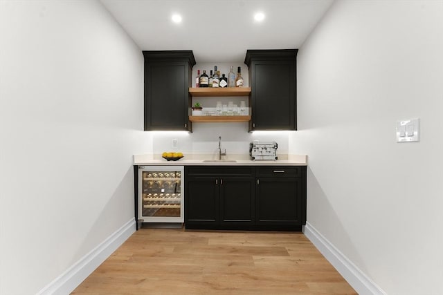 bar with wine cooler, sink, and light wood-type flooring