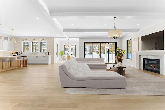 living room featuring an inviting chandelier, a healthy amount of sunlight, light hardwood / wood-style floors, and sink