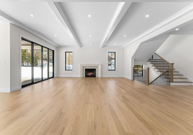 unfurnished living room with light hardwood / wood-style flooring, a wealth of natural light, and beamed ceiling