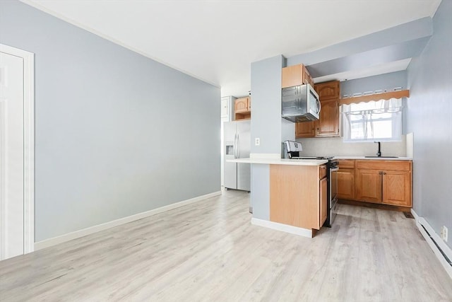 kitchen with appliances with stainless steel finishes, a baseboard heating unit, sink, and light wood-type flooring