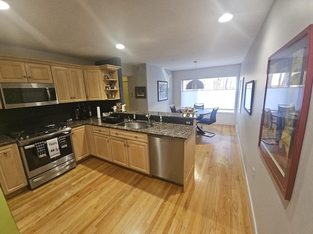 kitchen featuring sink, light wood-type flooring, kitchen peninsula, pendant lighting, and stainless steel appliances