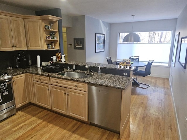 kitchen featuring appliances with stainless steel finishes, decorative light fixtures, sink, dark stone countertops, and kitchen peninsula