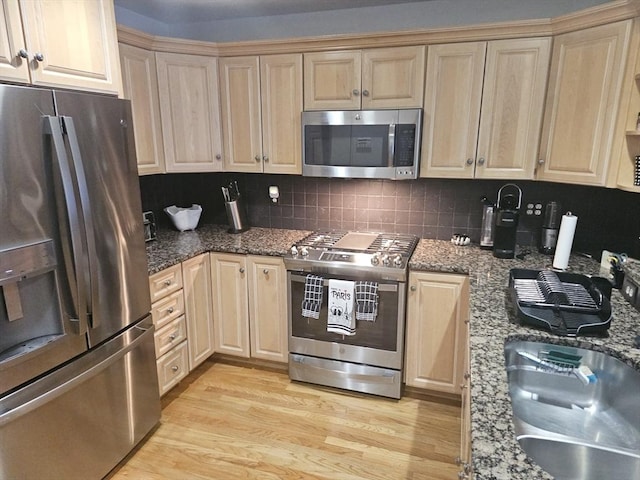 kitchen featuring sink, light hardwood / wood-style flooring, appliances with stainless steel finishes, backsplash, and stone countertops