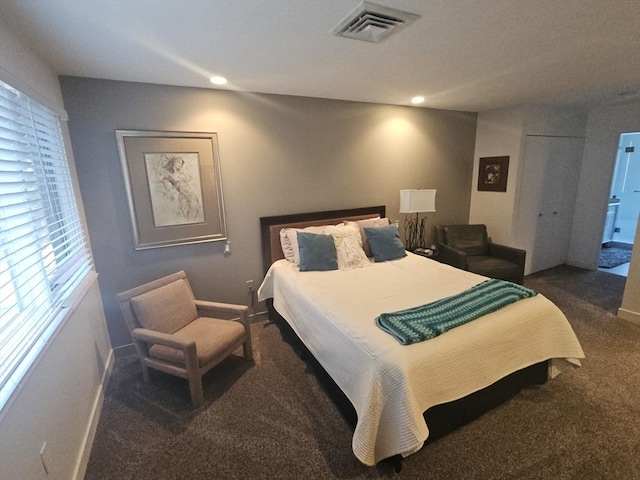 bedroom with ensuite bath and dark carpet