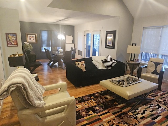 living room featuring vaulted ceiling, hardwood / wood-style floors, and a notable chandelier