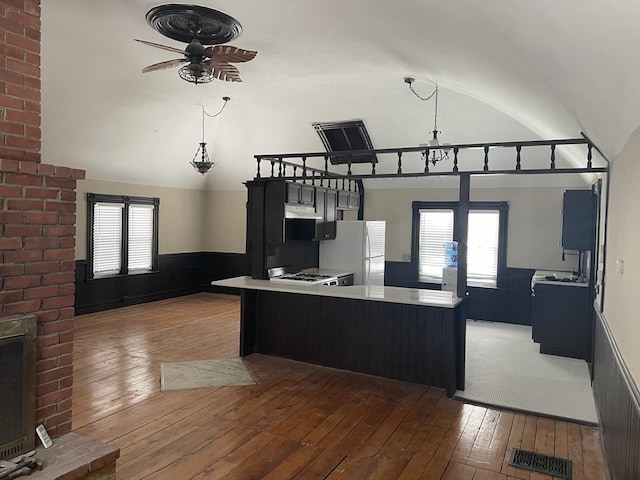 kitchen with freestanding refrigerator, wood-type flooring, a wainscoted wall, and vaulted ceiling