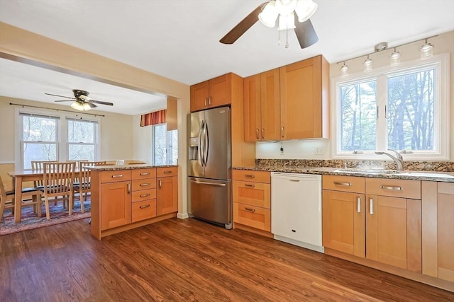 kitchen featuring stainless steel refrigerator with ice dispenser, dark wood-type flooring, sink, light stone counters, and dishwasher