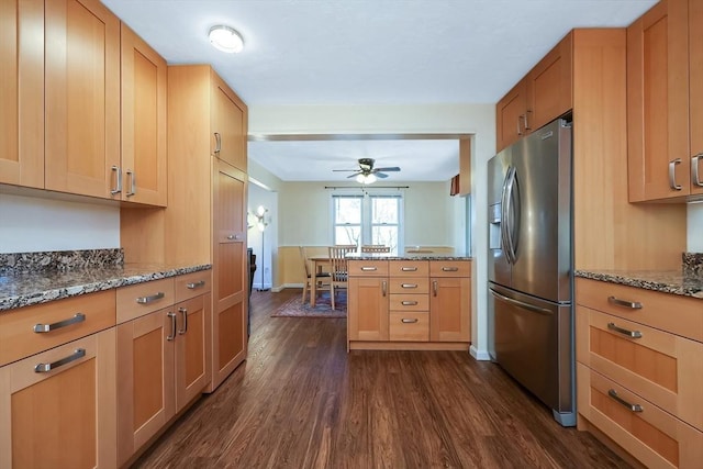 kitchen with stainless steel fridge, ceiling fan, light stone counters, dark hardwood / wood-style flooring, and kitchen peninsula