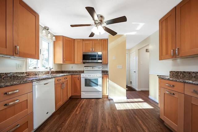 kitchen with sink, white appliances, ceiling fan, dark hardwood / wood-style flooring, and dark stone counters