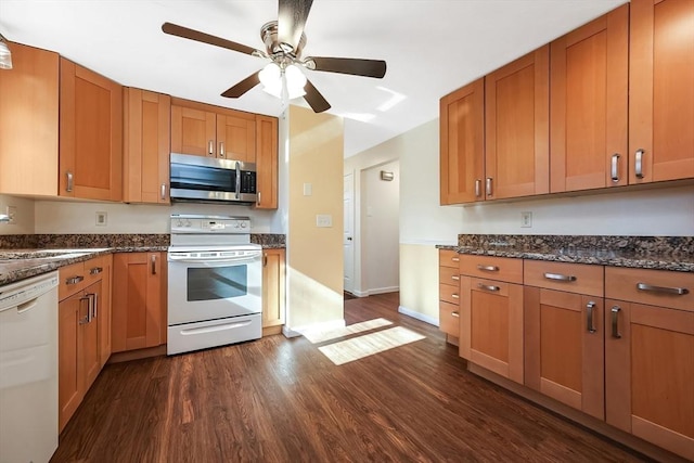 kitchen featuring dark stone countertops, sink, white appliances, and dark hardwood / wood-style floors