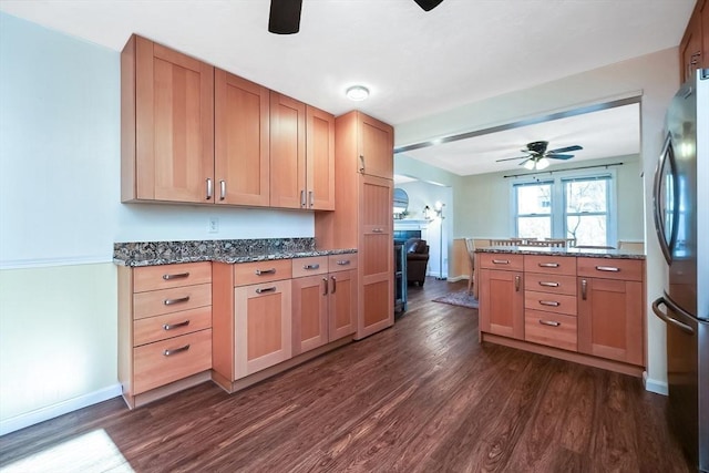 kitchen featuring dark hardwood / wood-style flooring, stainless steel fridge, dark stone counters, and ceiling fan