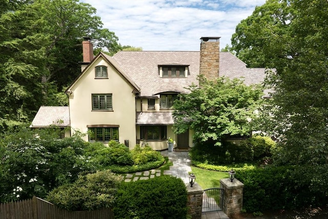 exterior space with a chimney, fence, a gate, and stucco siding