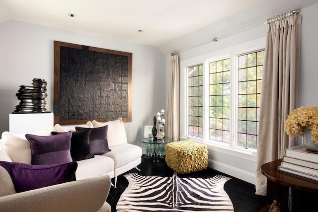 living area featuring vaulted ceiling, wood finished floors, and baseboards