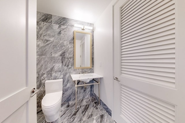 bathroom featuring tile walls and toilet