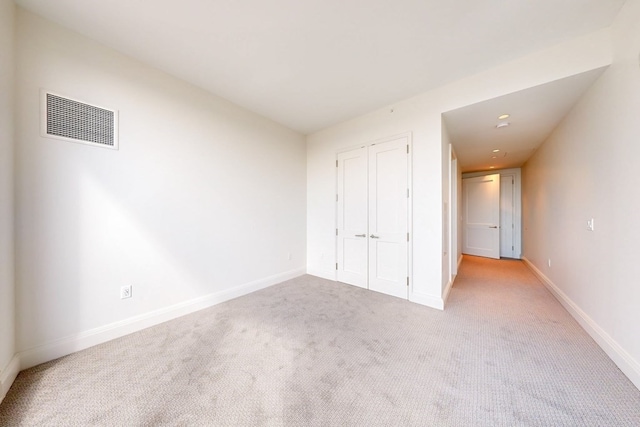 unfurnished bedroom with a closet and light colored carpet