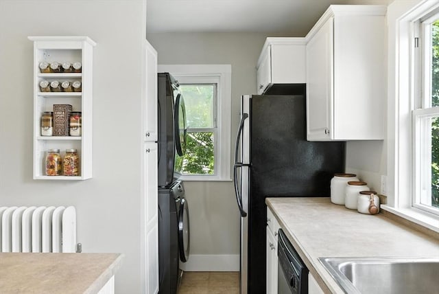 216 Cedar St Unit 3, Somerville, MA 02144 - kitchen featuring stacked washer / dryer, dishwasher, radiator, light countertops, and healthy amount of natural light