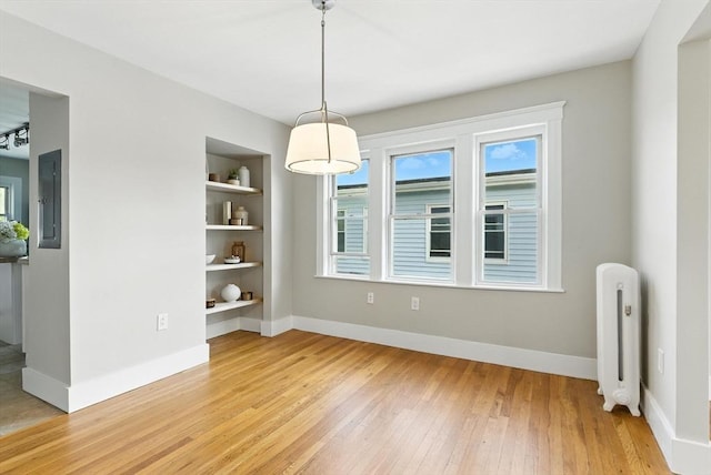 216 Cedar St Unit 3, Somerville, MA 02144 - unfurnished dining area featuring light wood-type flooring, built in shelves, electric panel, and radiator