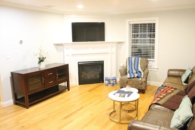 living area featuring crown molding, baseboards, wood finished floors, and a glass covered fireplace