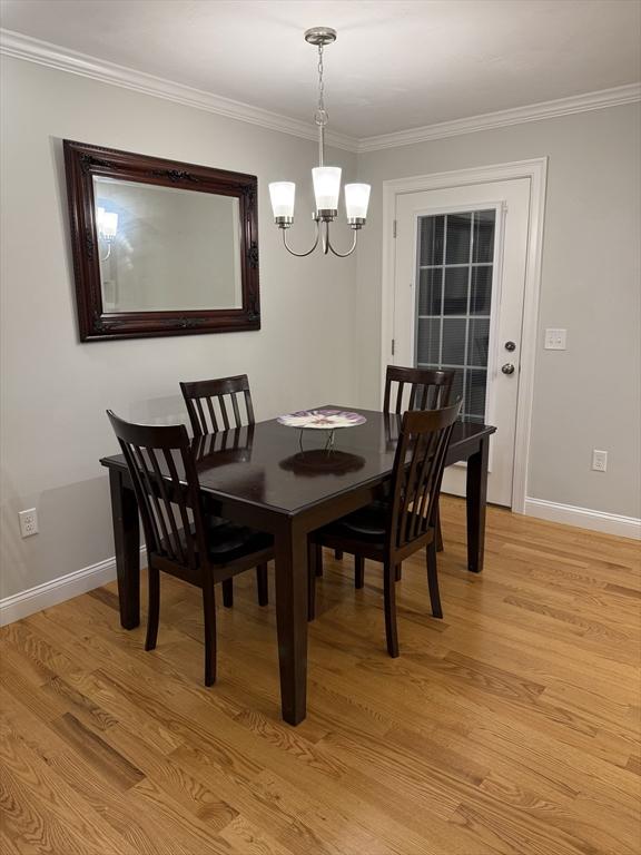 dining room with light wood-style flooring, baseboards, and crown molding