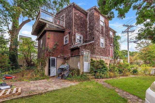 back of house with a balcony and a yard