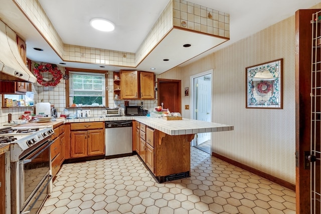 kitchen with tile countertops, range, stainless steel dishwasher, range hood, and kitchen peninsula