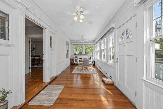 sunroom / solarium with a baseboard heating unit, wood finished floors, and a decorative wall
