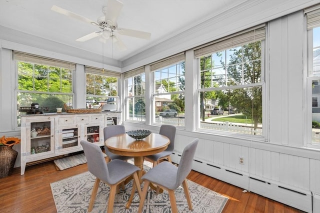 sunroom / solarium with a baseboard heating unit, a deck, wood finished floors, and ornamental molding