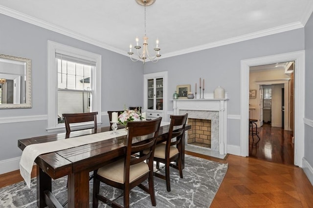 dining room featuring a chandelier, crown molding, a premium fireplace, and baseboards
