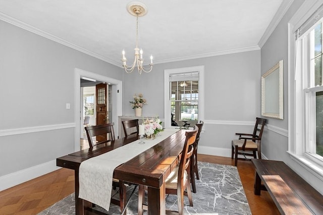 dining area with plenty of natural light, a chandelier, ornamental molding, and baseboards