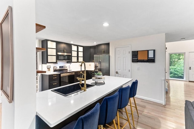 11 Running Stream Rd, Rehoboth, MA 02769 - kitchen with stainless steel appliances, light wood finished floors, a breakfast bar, light countertops, and backsplash