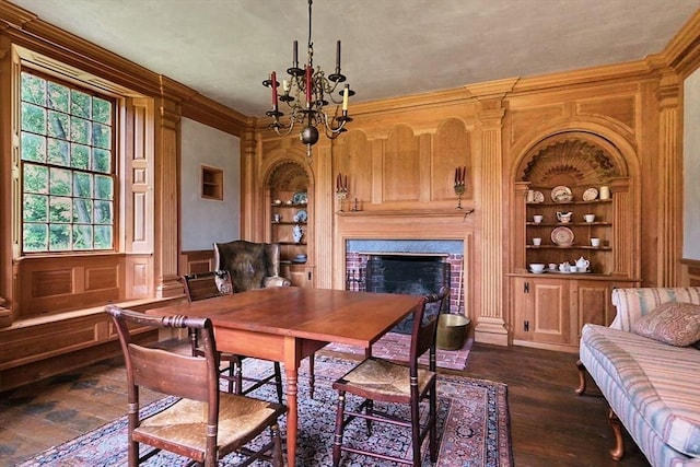 dining room featuring built in features, dark wood-type flooring, a chandelier, and a fireplace