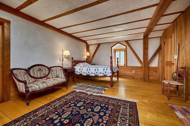 bedroom with beam ceiling, wood walls, and hardwood / wood-style flooring