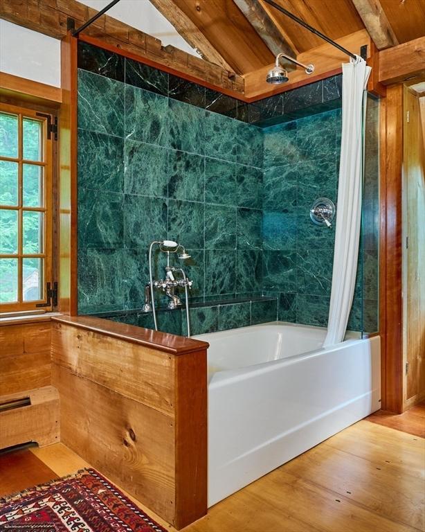 bathroom with lofted ceiling, wood finished floors, and shower / tub combo