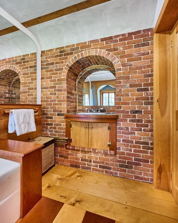 bathroom featuring brick wall, vanity, and wood-type flooring