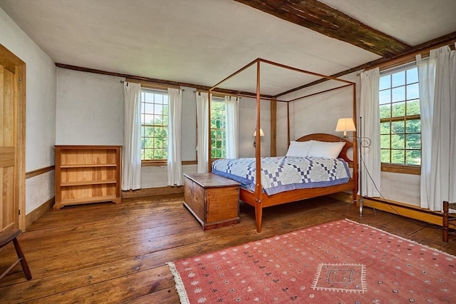 bedroom with beam ceiling, multiple windows, and hardwood / wood-style flooring