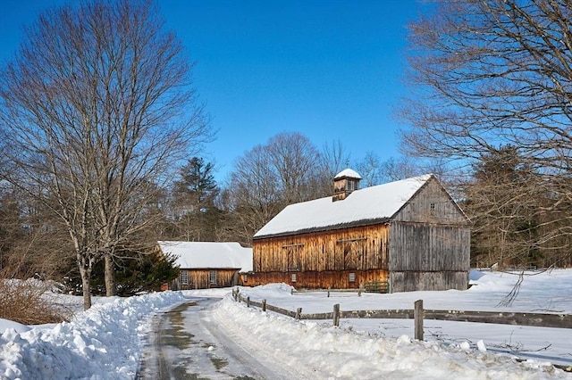 view of snow covered exterior with a garage, an outbuilding, and a barn