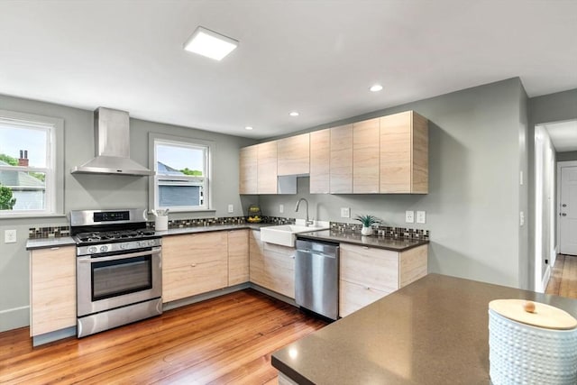 21 Plainfield St Unit 3, Boston, MA 02130 - kitchen with stainless steel appliances, wall chimney exhaust hood, a sink, light brown cabinetry, and light wood-style flooring