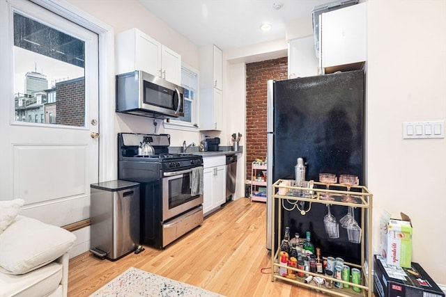 kitchen with white cabinets, light wood-type flooring, and stainless steel appliances