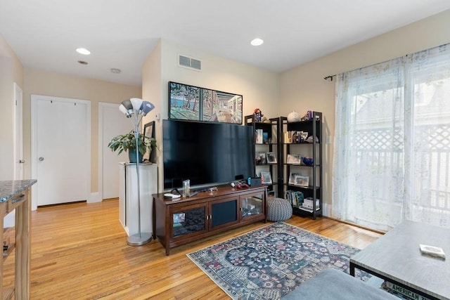 living room with recessed lighting, visible vents, and wood finished floors