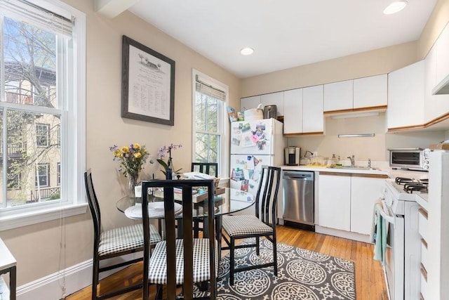 kitchen with a sink, light countertops, white cabinets, and white appliances