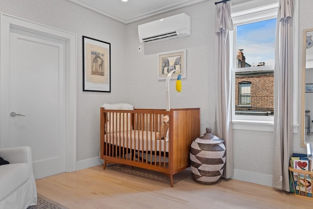 bedroom featuring light hardwood / wood-style flooring, a wall unit AC, multiple windows, and a crib