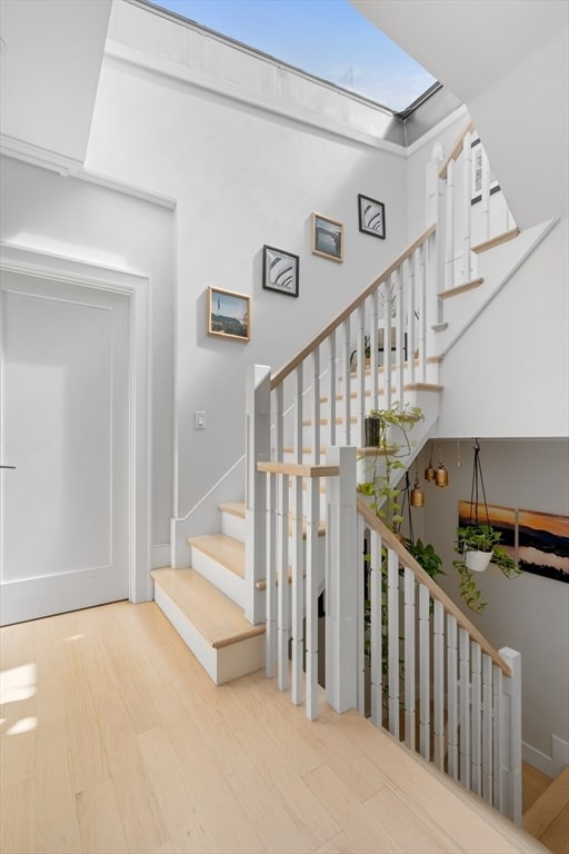 stairs featuring a skylight and hardwood / wood-style flooring