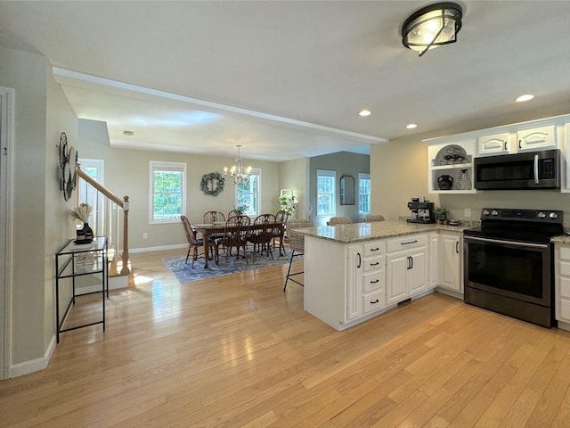 111 Country Club Pl, Southbridge, MA 01550 - kitchen with stainless steel microwave, range with electric cooktop, a peninsula, light wood-style flooring, and white cabinetry