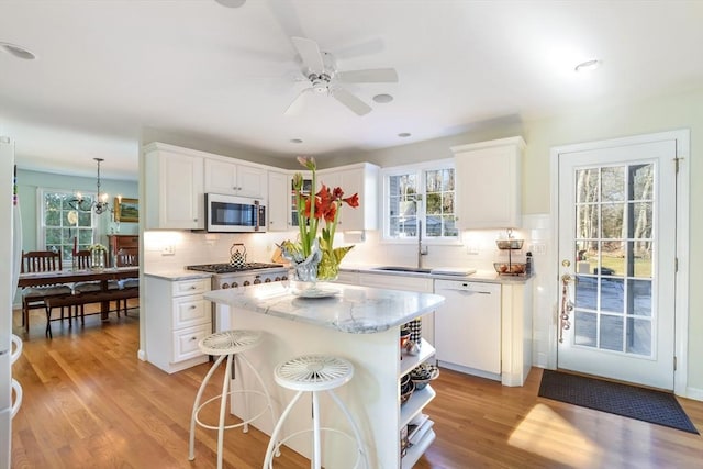 kitchen with white appliances, a center island, white cabinetry, backsplash, and hanging light fixtures