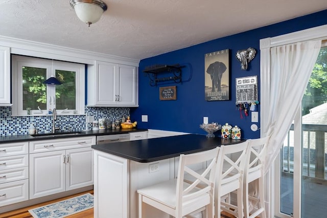 29 Wituwamat Rd, Weymouth, MA 02191 - kitchen featuring a sink, dark countertops, a kitchen bar, tasteful backsplash, and white cabinets
